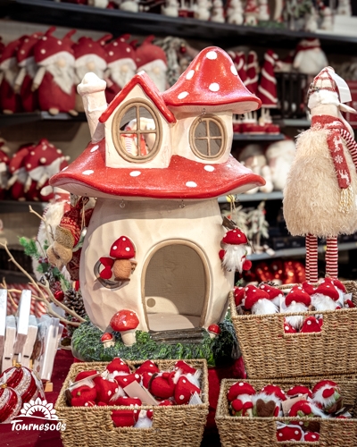 Maison champignon décorative rouge à pois blancs entourée de paniers de champignons de Noël en jardinerie Tournesols